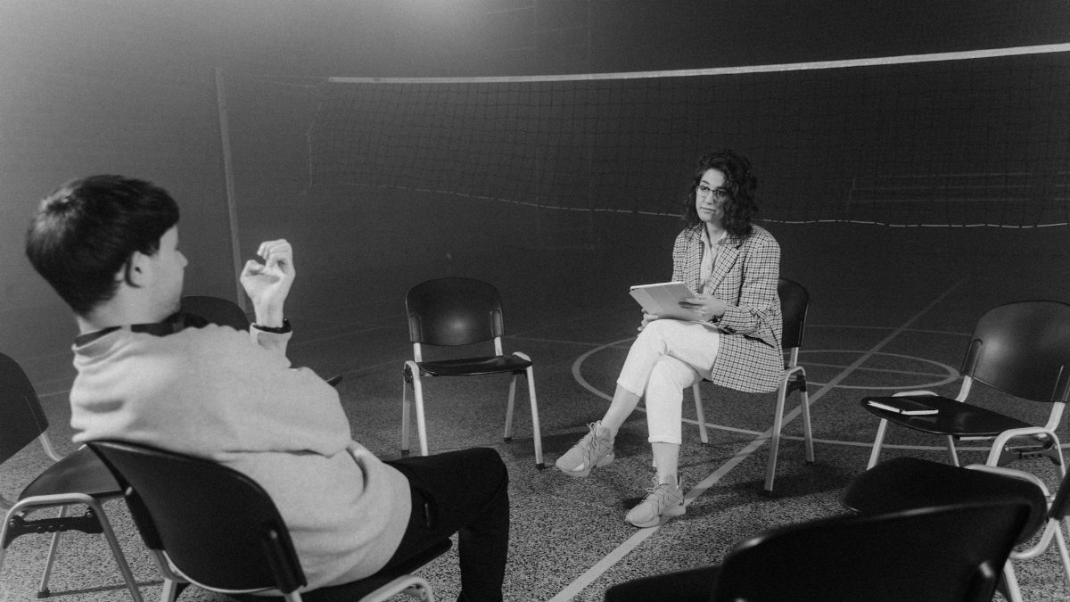 A black and white image capturing a one-on-one counseling session in an indoor setting.