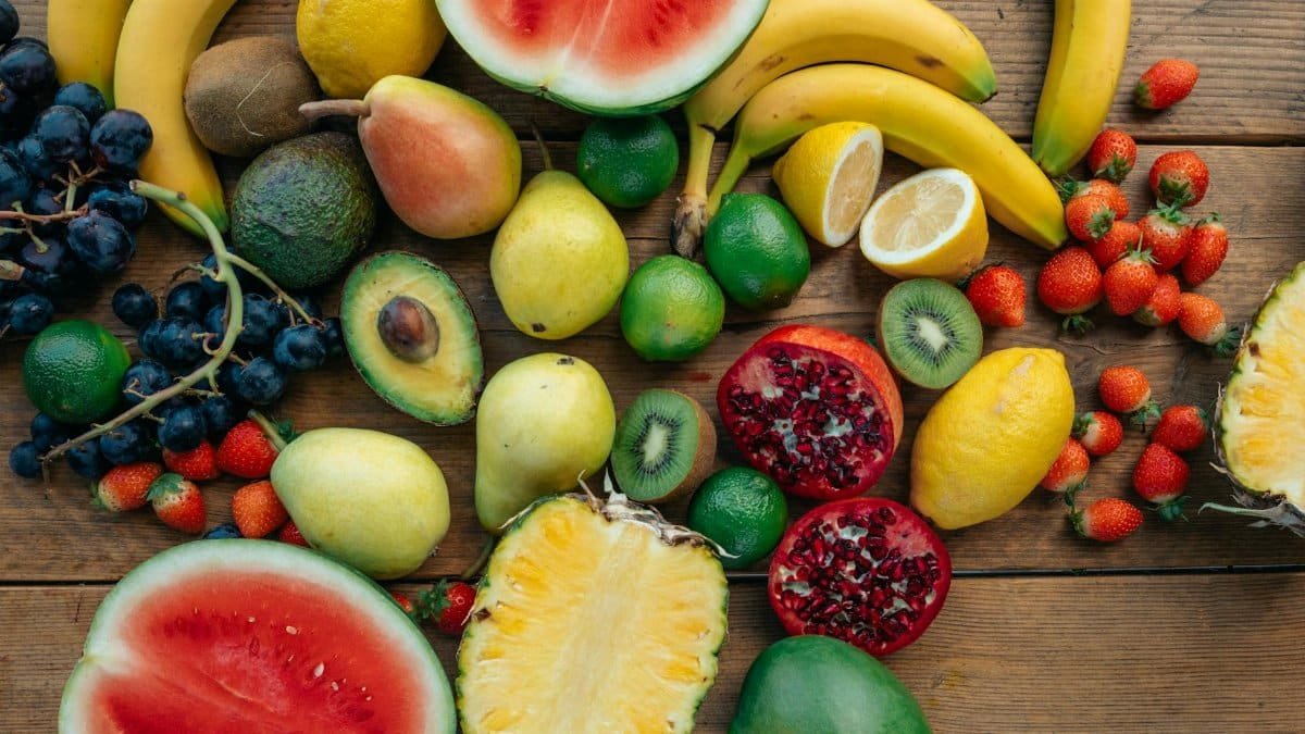 Colorful variety of fresh fruits including watermelon, pineapple, and grapes on a wooden surface.