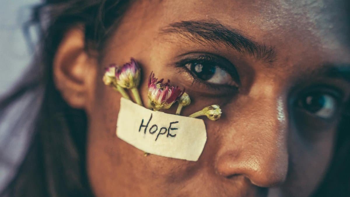 Close-up portrait with flowers and 'Hope' message on face. Captured in a unique and meaningful style.