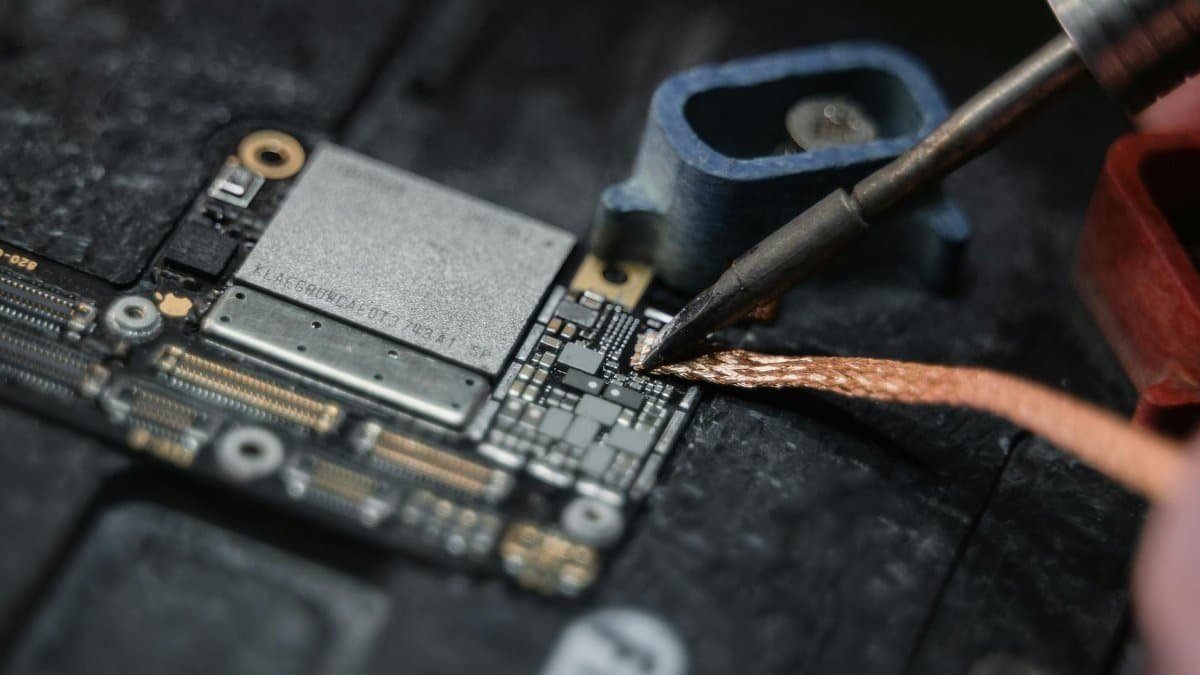 Detailed close-up of a soldering iron working on a circuit board, showcasing electronics repair.