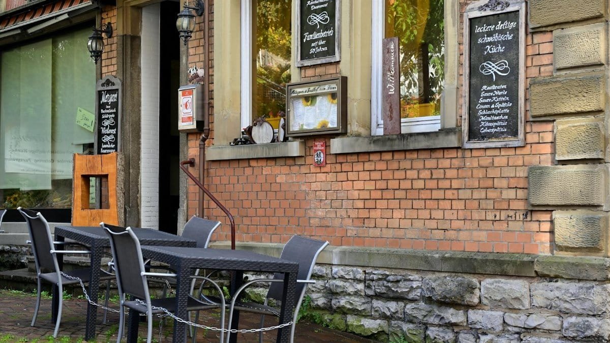 Cozy outdoor seating area of a restaurant with a brick facade featuring classic decor and menu boards.