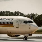 Singapore Airlines plane taxiing on airport runway under cloudy skies.