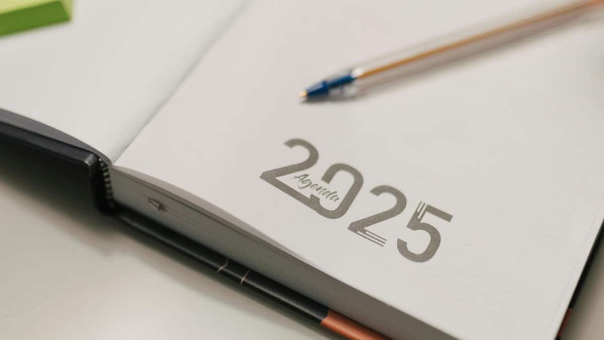 Open 2025 agenda book with a blue pen on a desk, ideal for organization and planning.