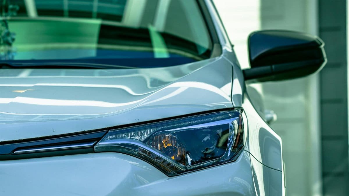 Detailed view of a stylish white car's headlight with reflective sleek design.