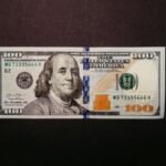 Close-up of a US 100 dollar bill displayed on a black background.