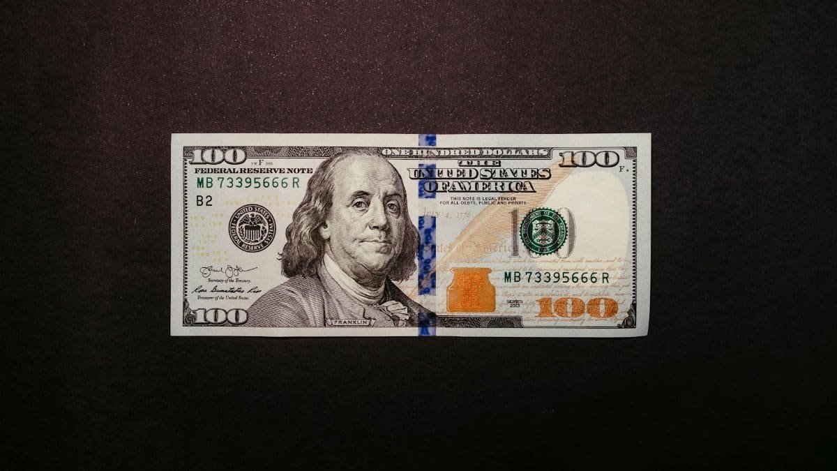 Close-up of a US 100 dollar bill displayed on a black background.