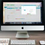A sleek office setup featuring an Apple iMac, iPad, and keyboard on a wooden desk.