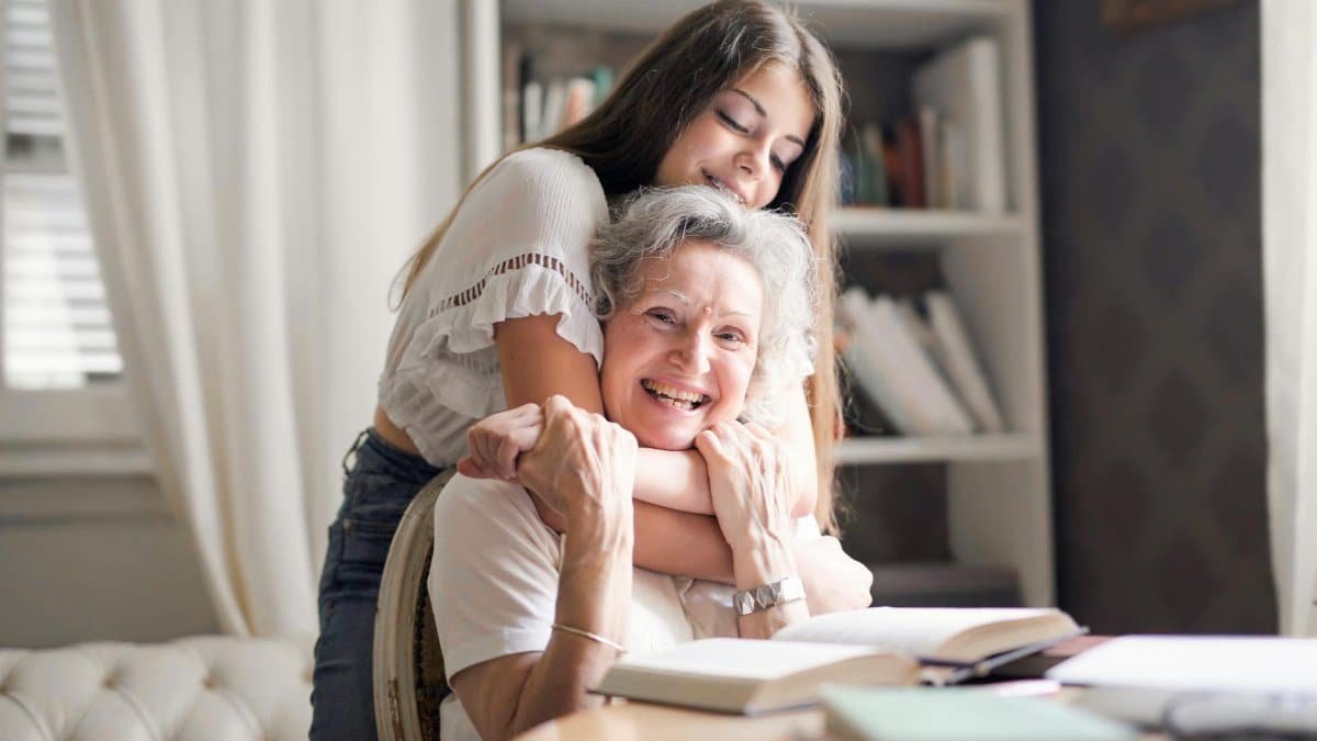 A joyful moment of a granddaughter hugging her grandma at home, showcasing love and family bond.