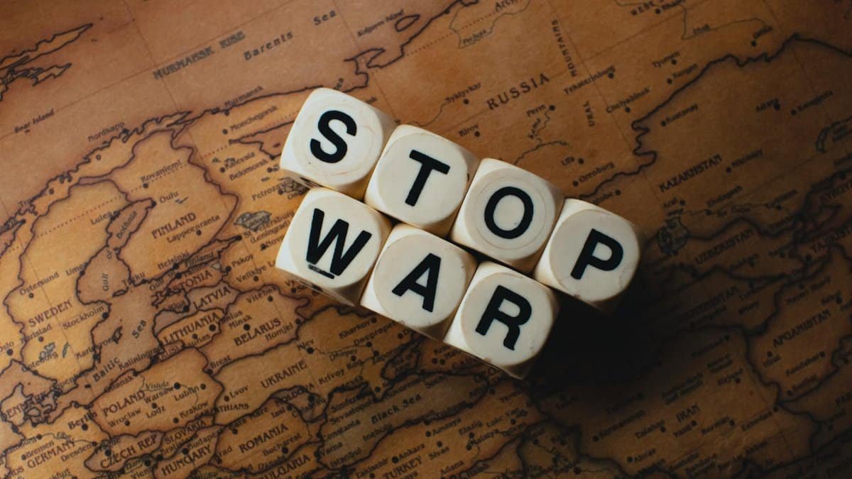 Dice with 'STOP WAR' on a vintage world map signifies peace.