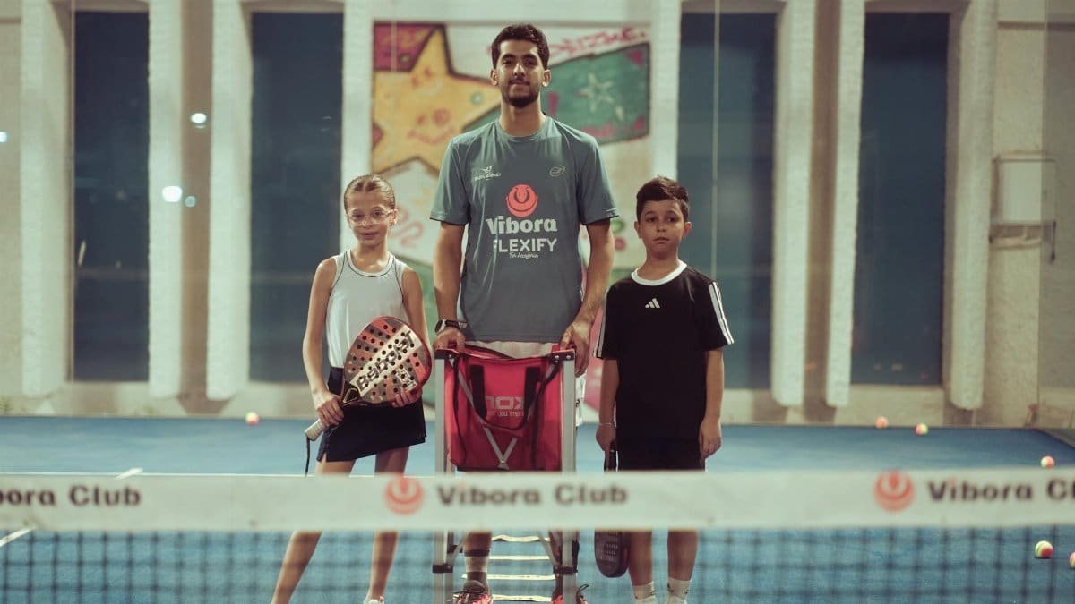 Tennis coach with two young players indoors at Vibora Club.
