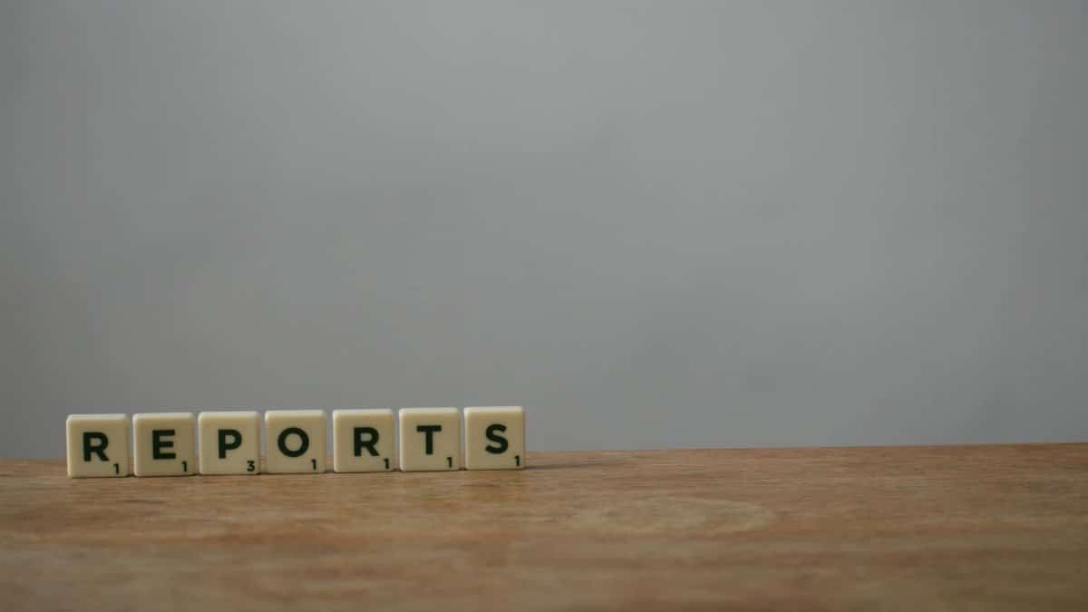 Scrabble tiles spelling 'reports' on a wooden desk, ideal for office or business themes.