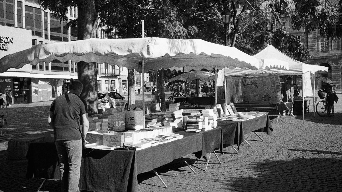 Charming outdoor book market in Strasbourg, France, captured in black and white.