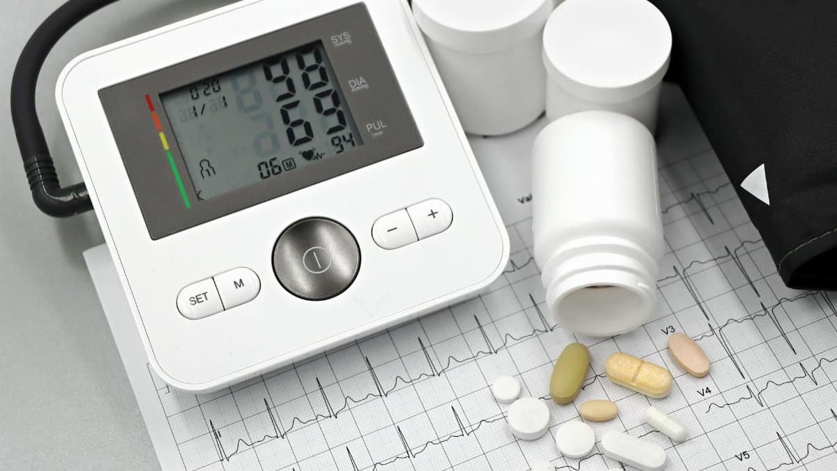 Blood pressure monitor with pills on ECG sheet, essential for heart health management.