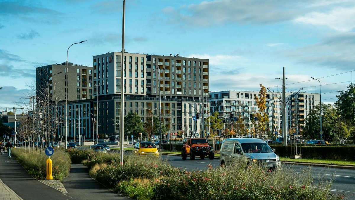 Vibrant cityscape featuring contemporary high-rise apartments, busy street, and lush greenery.