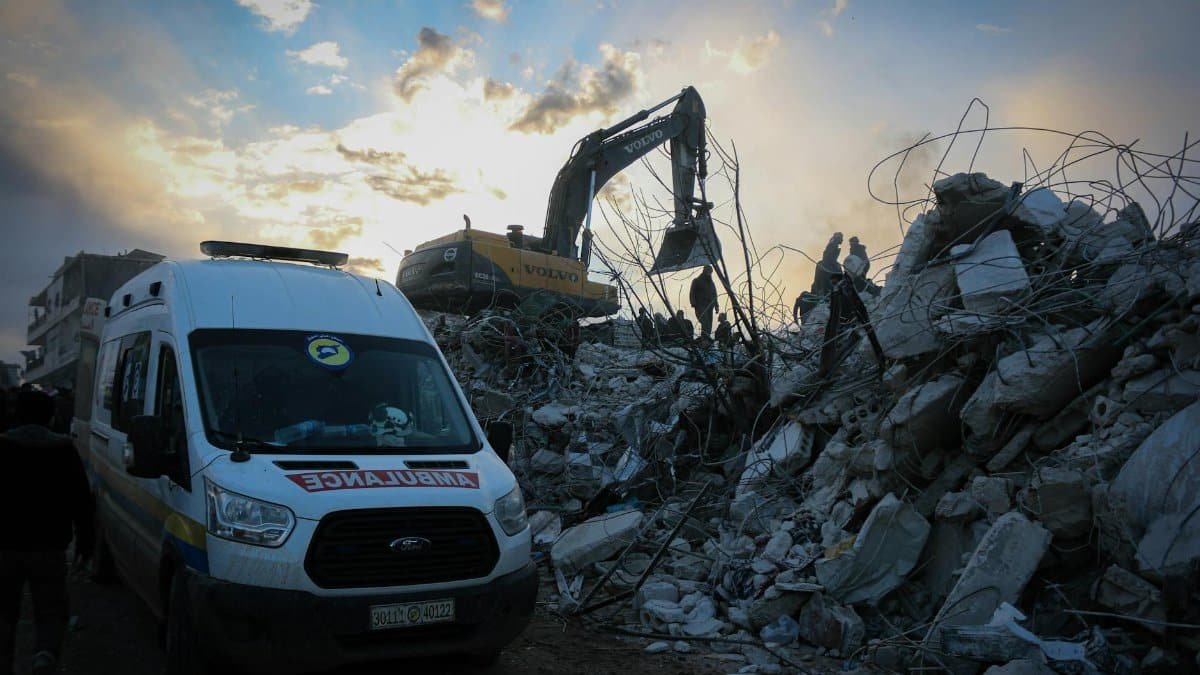 Emergency responders clear rubble in Idlib, Syria after a natural disaster. Scene highlights urgency and recovery efforts.