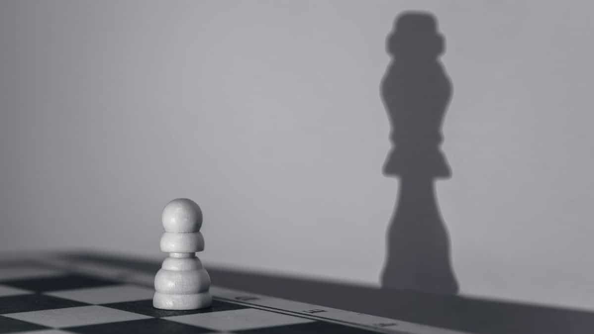 White chess pawn casting a shadow of a queen, symbolizing growth and transformation.