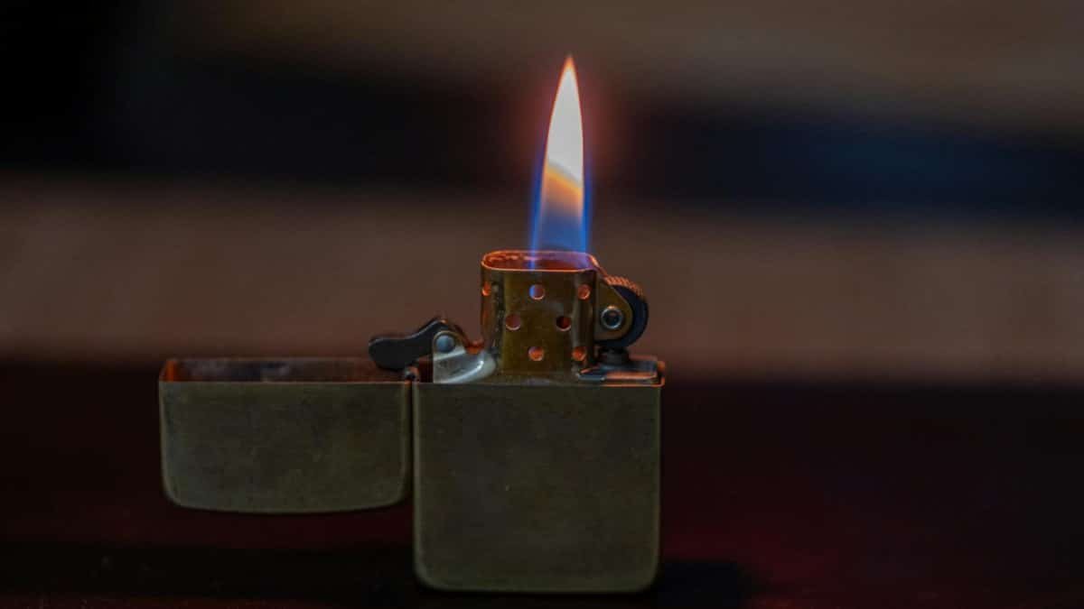 Captivating image of an open metallic lighter with a bright flame against a dark background.