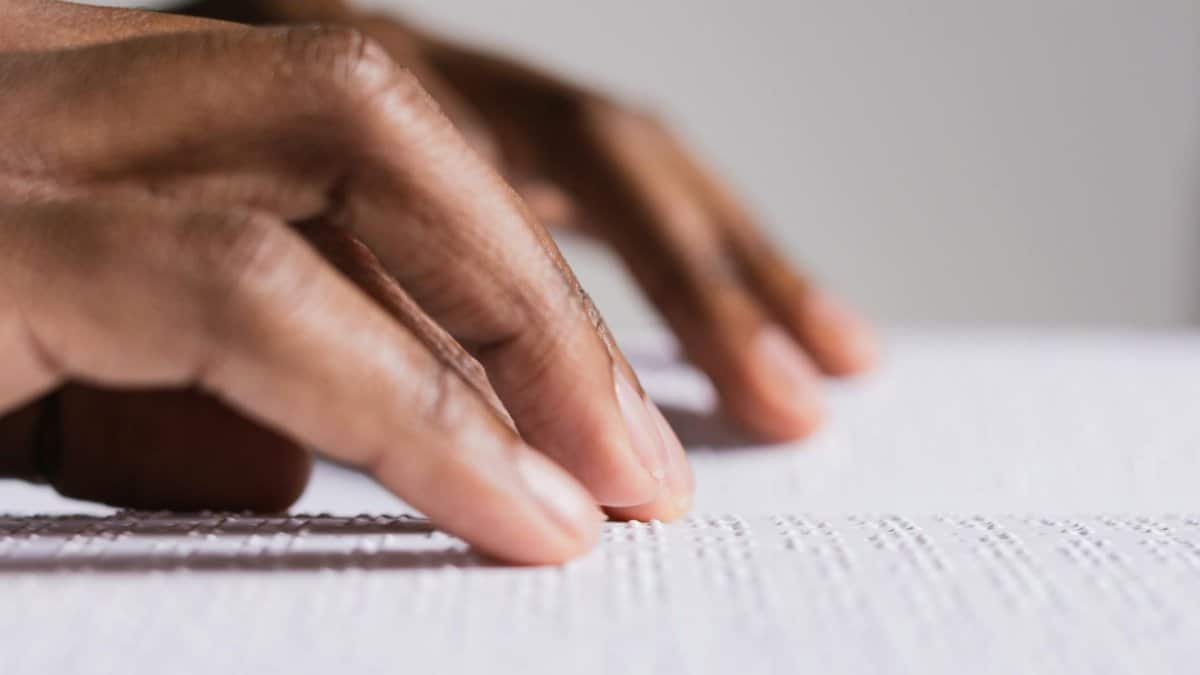 Hands touching and reading Braille text, highlighting tactile learning and accessibility.