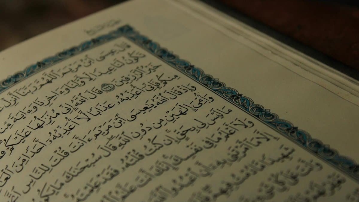 Intricate Arabic calligraphy on an open page of a religious book, showcasing artistic detail.