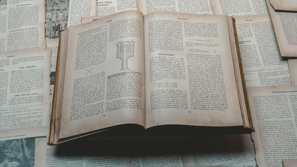 Explore a classic open book surrounded by vintage papers, perfect for historical and educational themes.