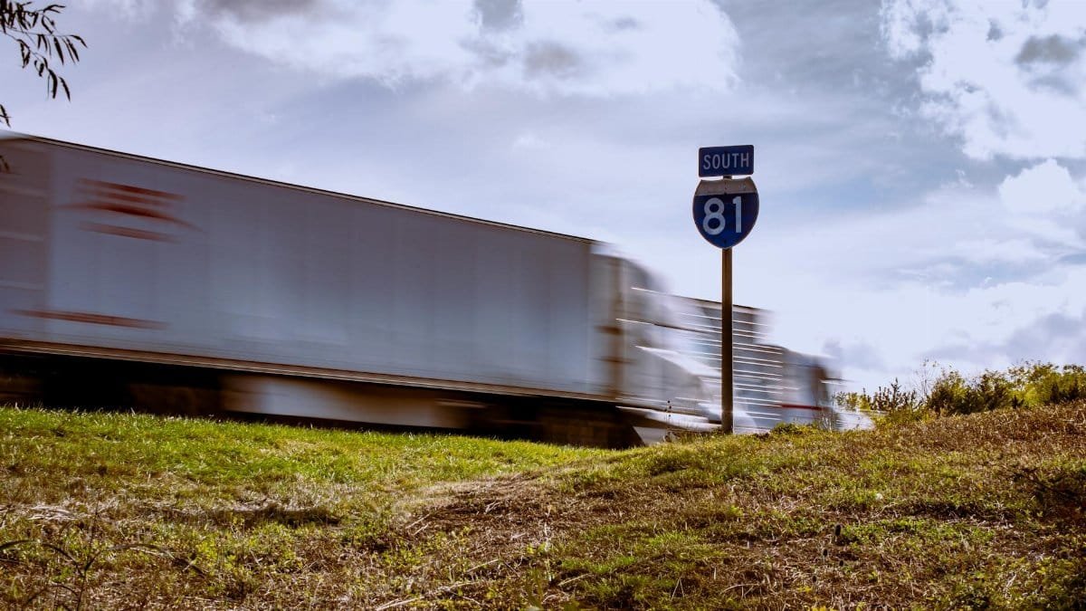 Blurred truck on Interstate 81 South with clear blue sky and grassy foreground.
