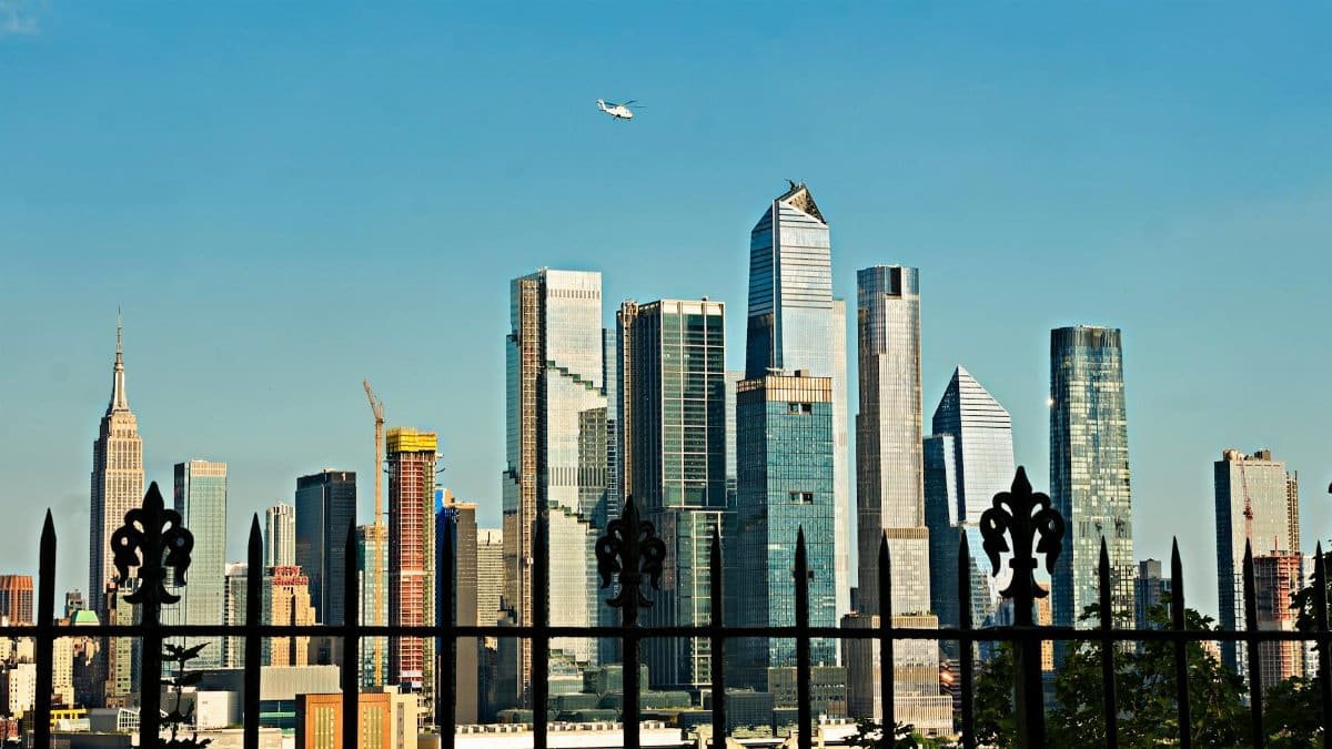 Majestic view of New York City's skyline from Hoboken, featuring prominent skyscrapers and blue sky.