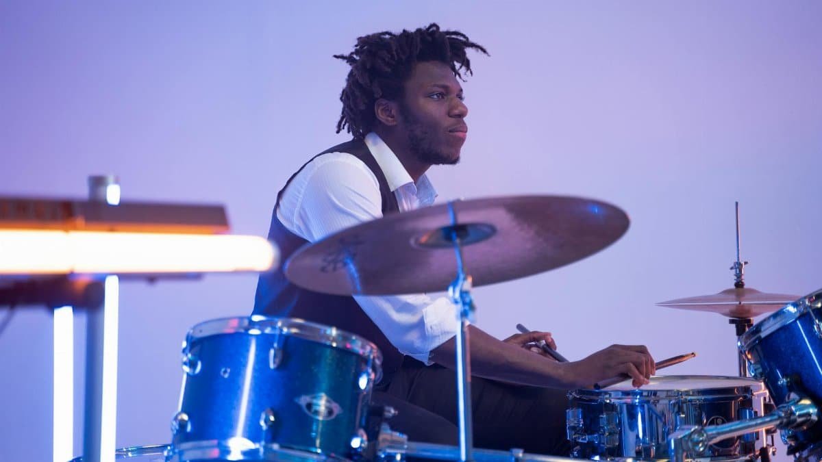 A talented drummer performing passionately on stage with vibrant lighting.