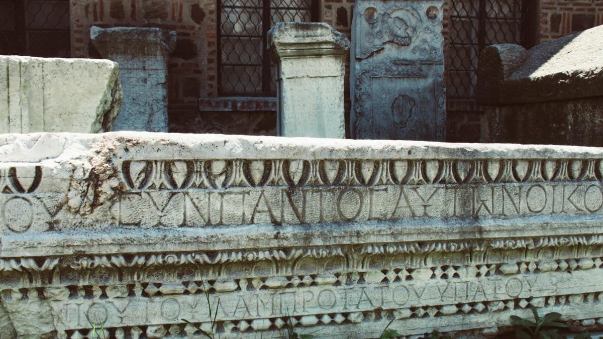 Close-up of an ancient Roman stone inscription with intricate carvings and Latin text.