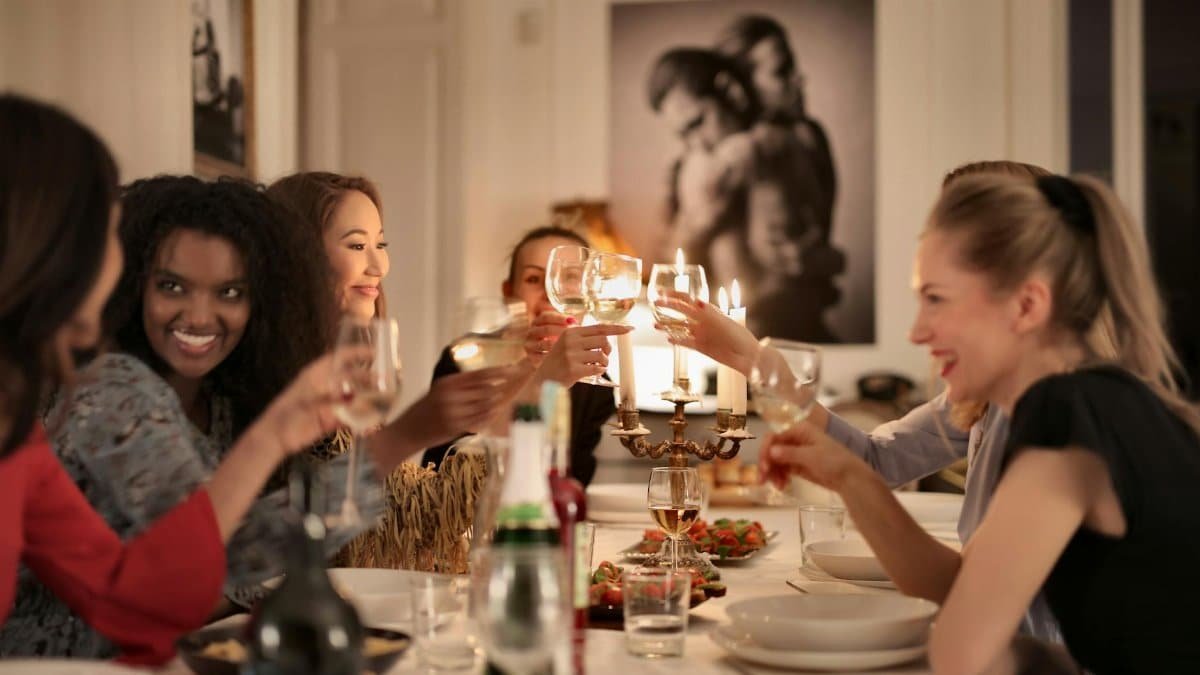 A group of friends enjoying a dinner party, toasting with wine glasses around a candlelit table.