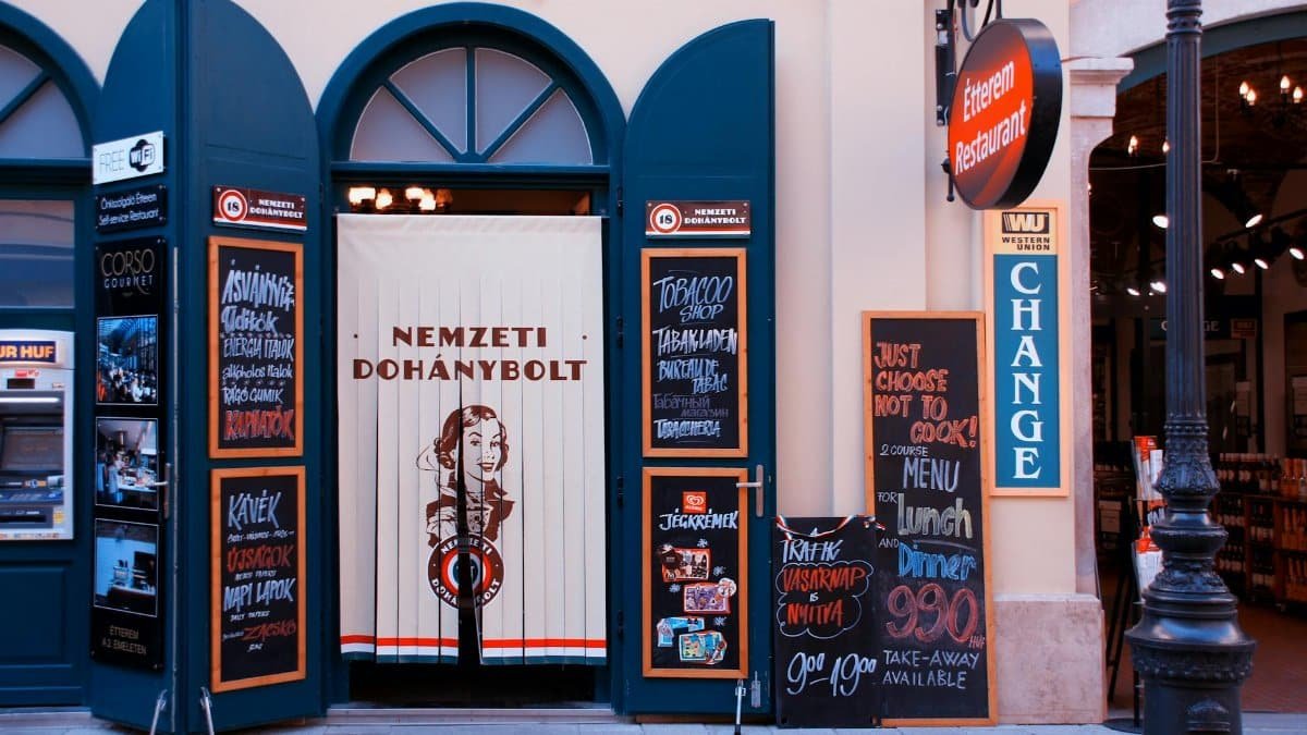 Colorful storefront of a tobacco shop and restaurant in a European city with vibrant signage.