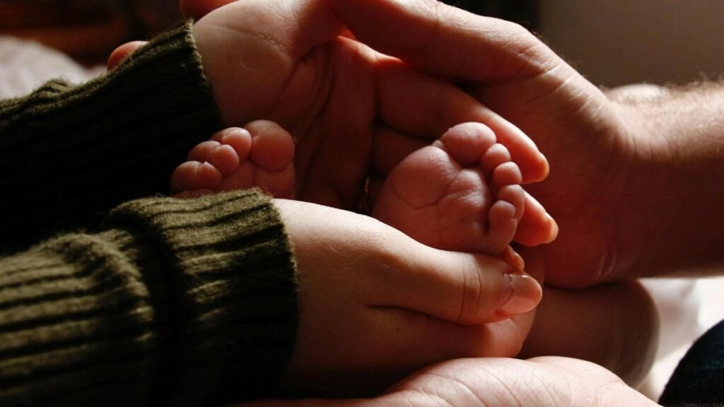 Close-up of baby feet held by adult hands, symbolizing family love and care.