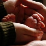 Close-up of baby feet held by adult hands, symbolizing family love and care.