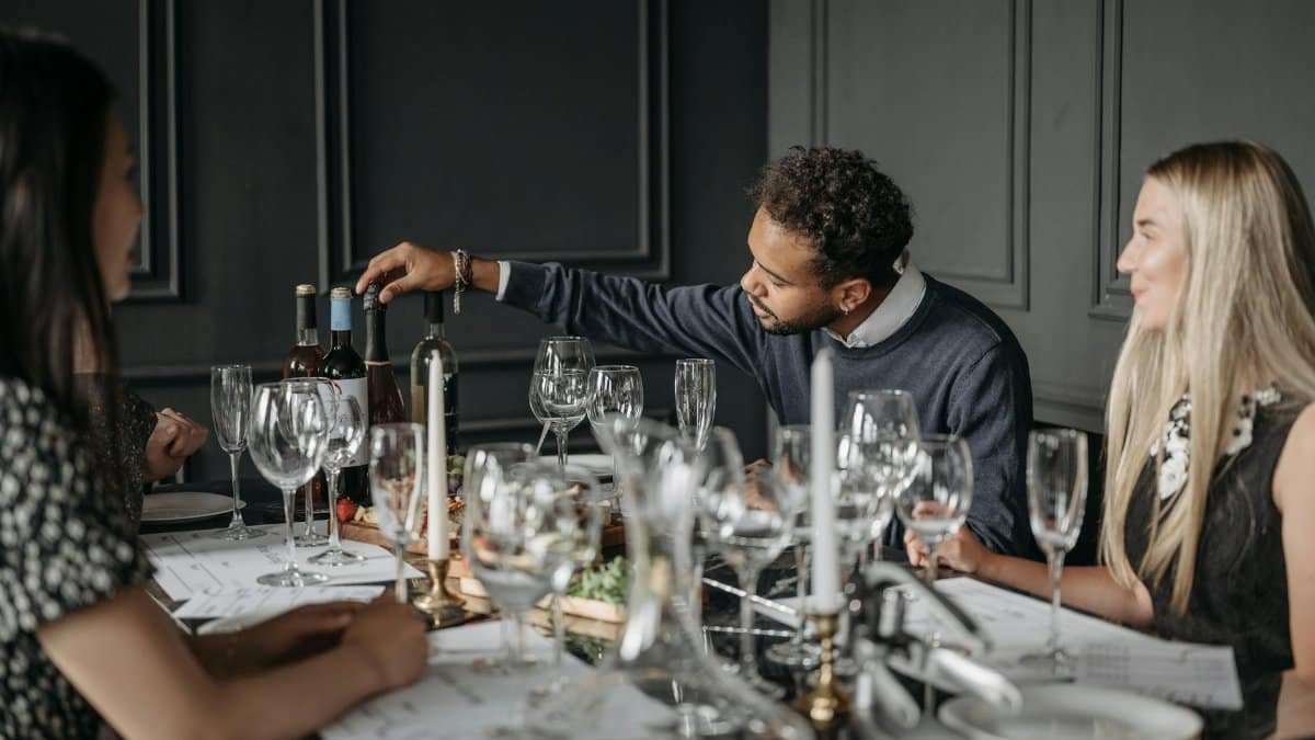 A diverse group of adults enjoying a dinner party indoors with wine and candles.