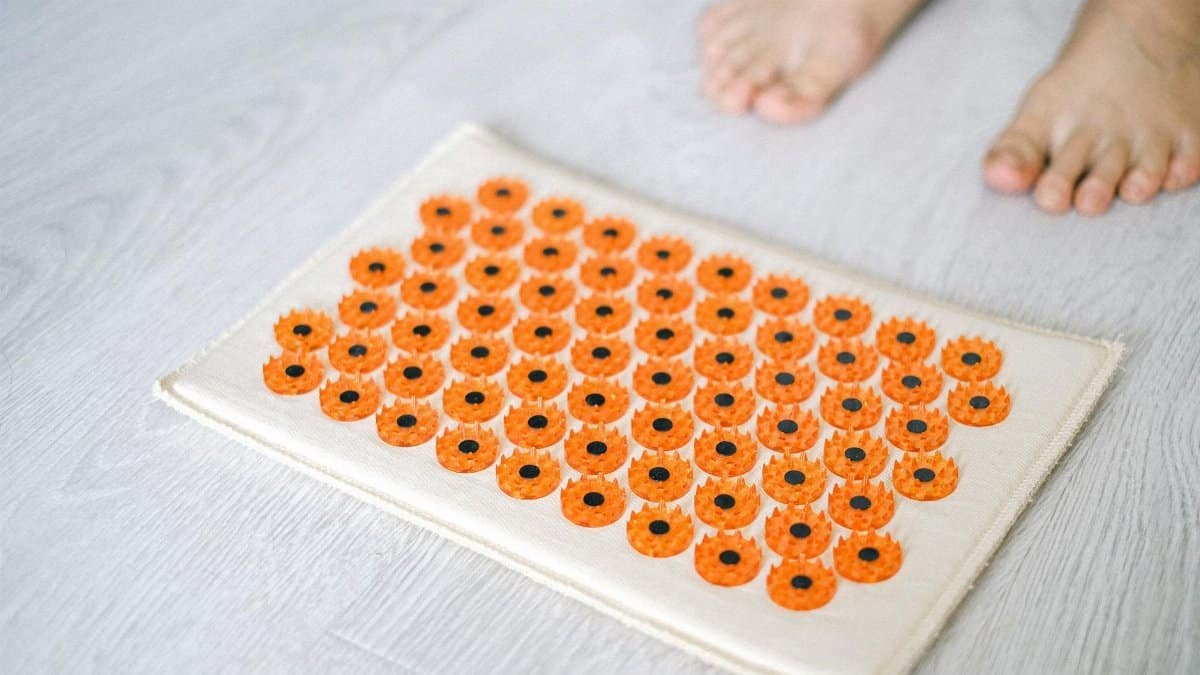 Close-up of a foot acupressure mat on a wooden floor, ideal for relaxation therapies.