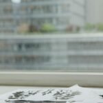 A minimalist office desk setup featuring psychological test papers, a glass of water, and a pen.