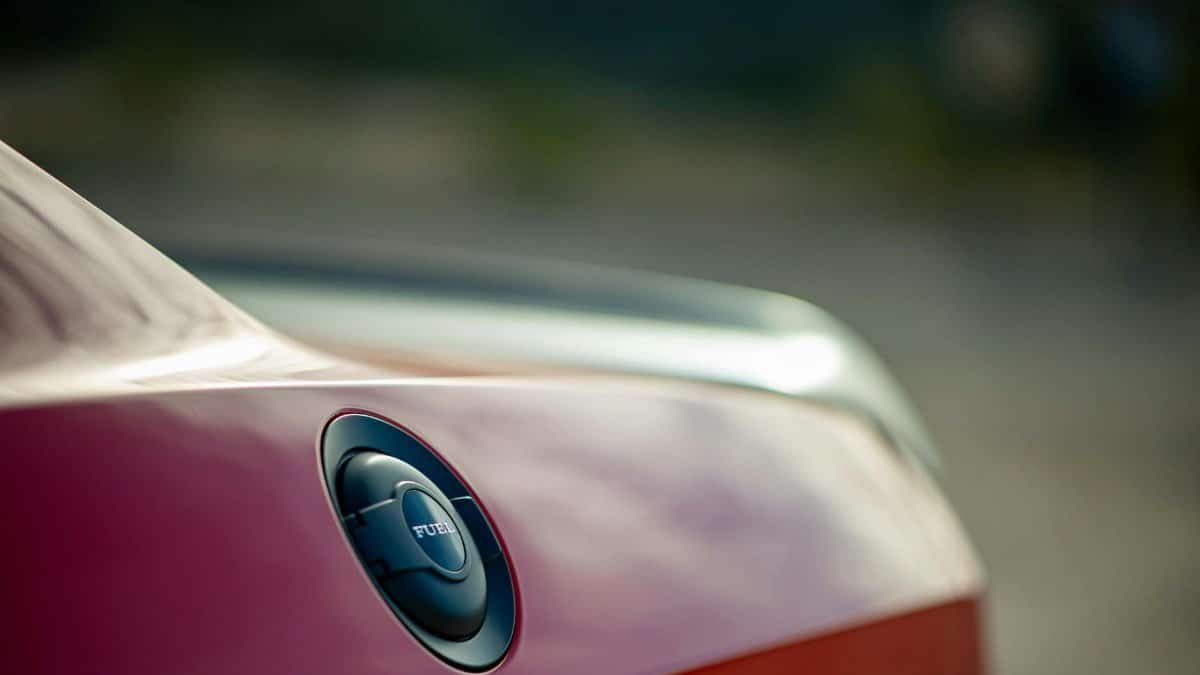 Detailed view of a red Dodge Challenger fuel cap with blurred background, emphasizing automotive design.
