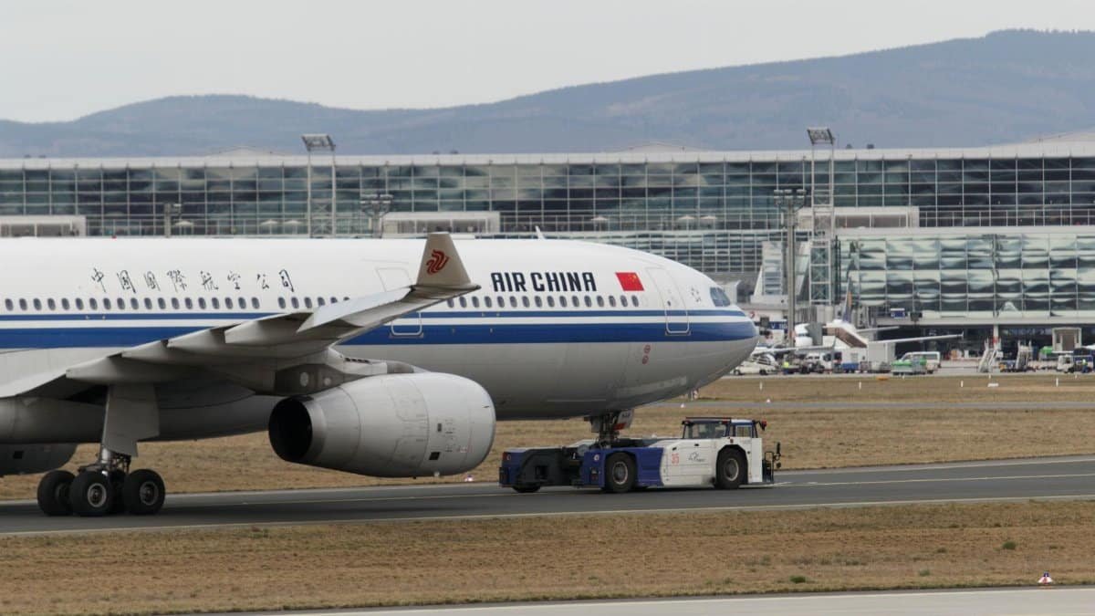 Air China aircraft being towed at Frankfurt Airport with terminal in view.