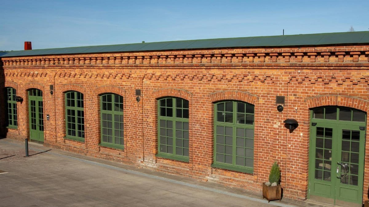A charming red brick building with green windows in Jönköping, Sweden, under clear blue skies.