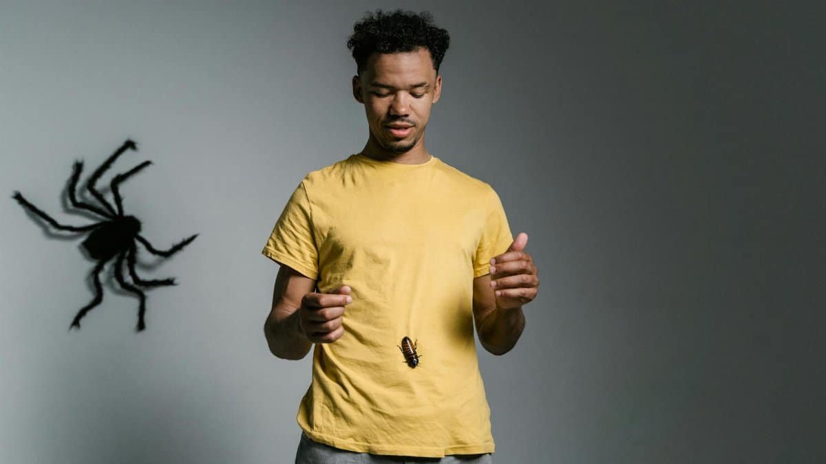 Man confronts phobia with cockroach on shirt; tackling fear and anxiety