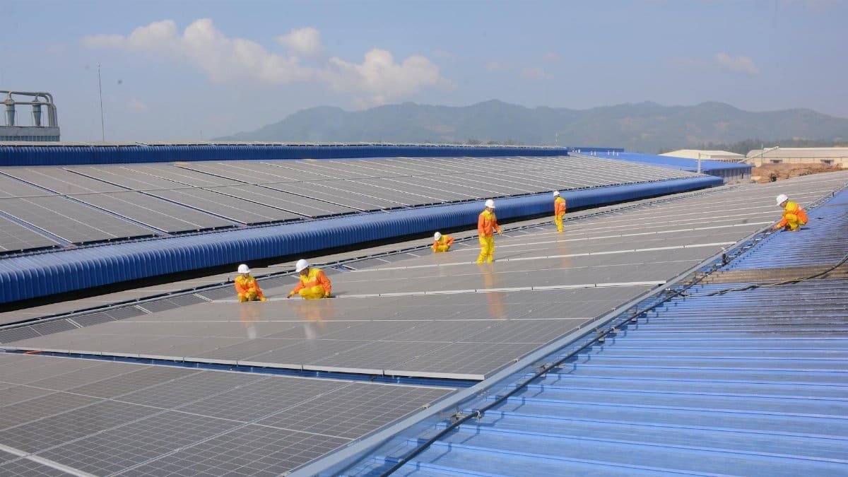 Workers installing solar panels on a large roof, highlighting renewable energy and sustainability.
