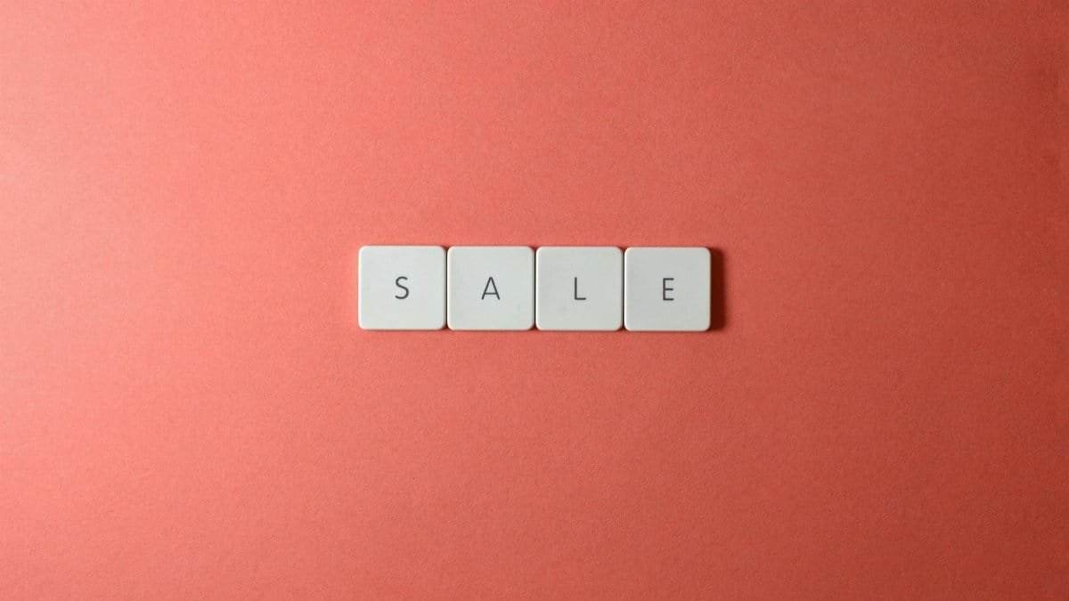 A minimalist flat lay of the word SALE spelled with letter tiles on a red background, perfect for promotions.