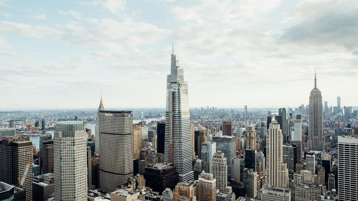 Drone view of modern high rise houses and empire state building located against cloudy sky in downtown of New York city