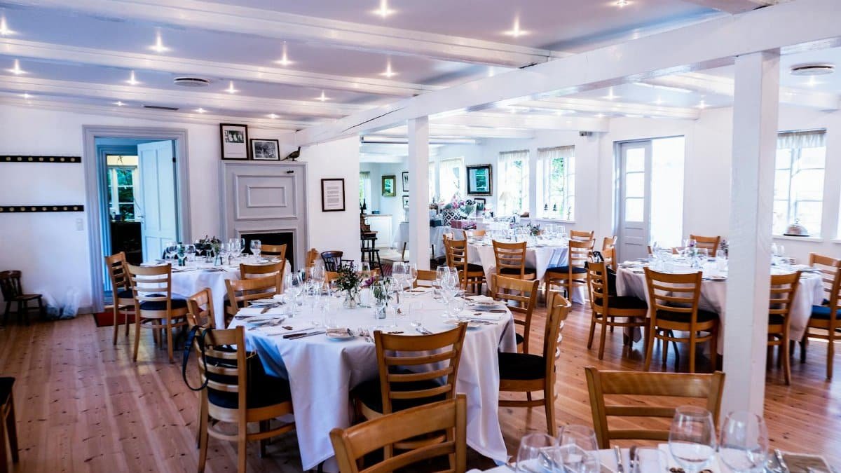 Charming wedding reception setup with round tables, wooden chairs, and elegant tableware.