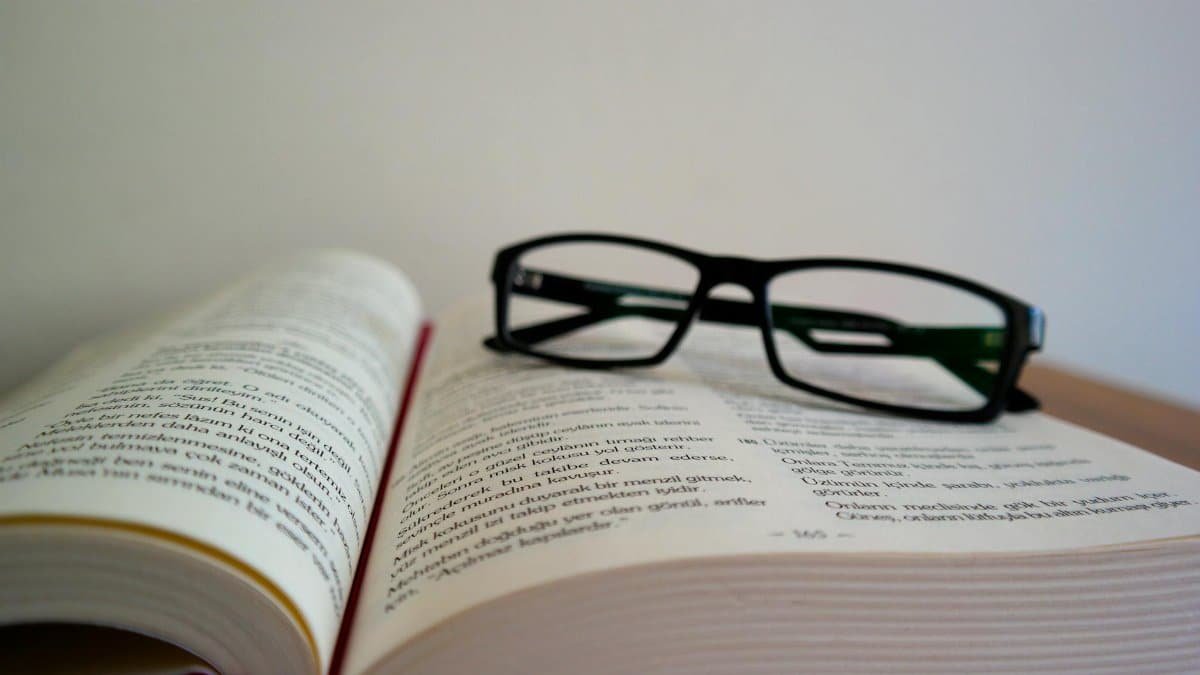 An open book with eyeglasses resting on top, symbolizing learning and education.