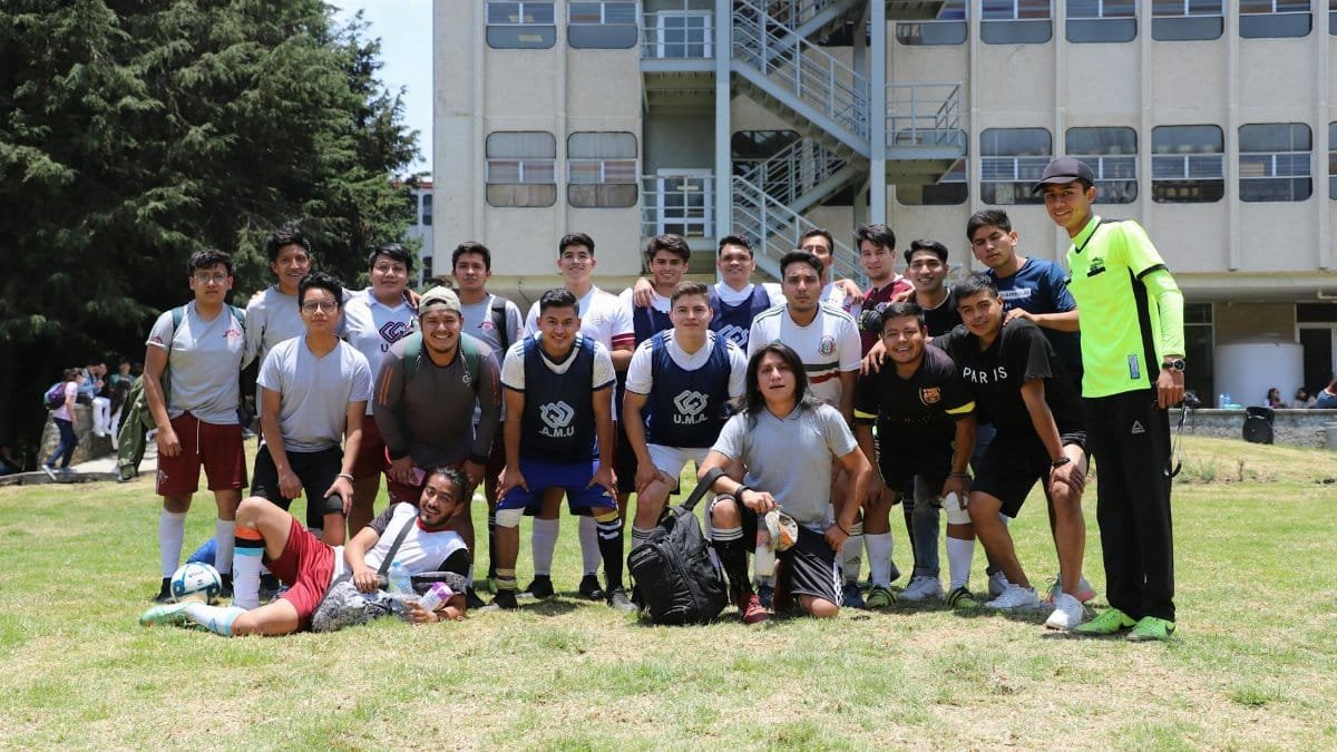 A group of young men posing as a soccer team outdoors on a sunny day.