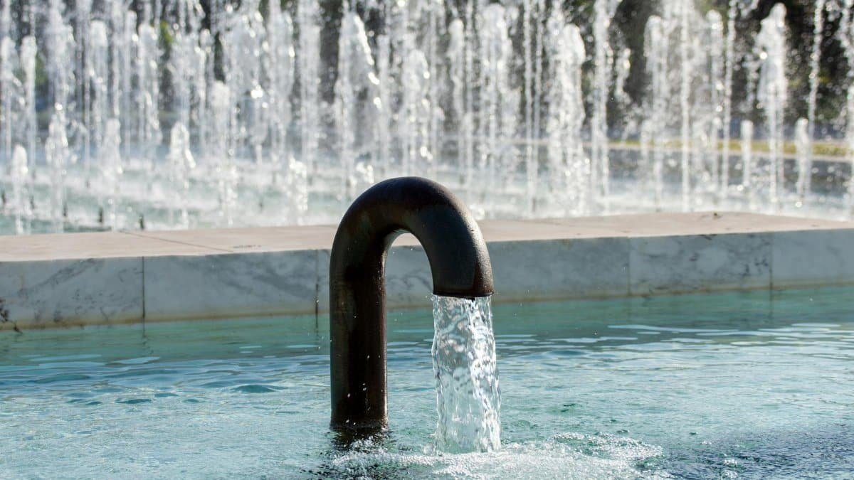 Capture of an elegant water fountain featuring an arched pipe with cascading water, perfect for urban design themes.