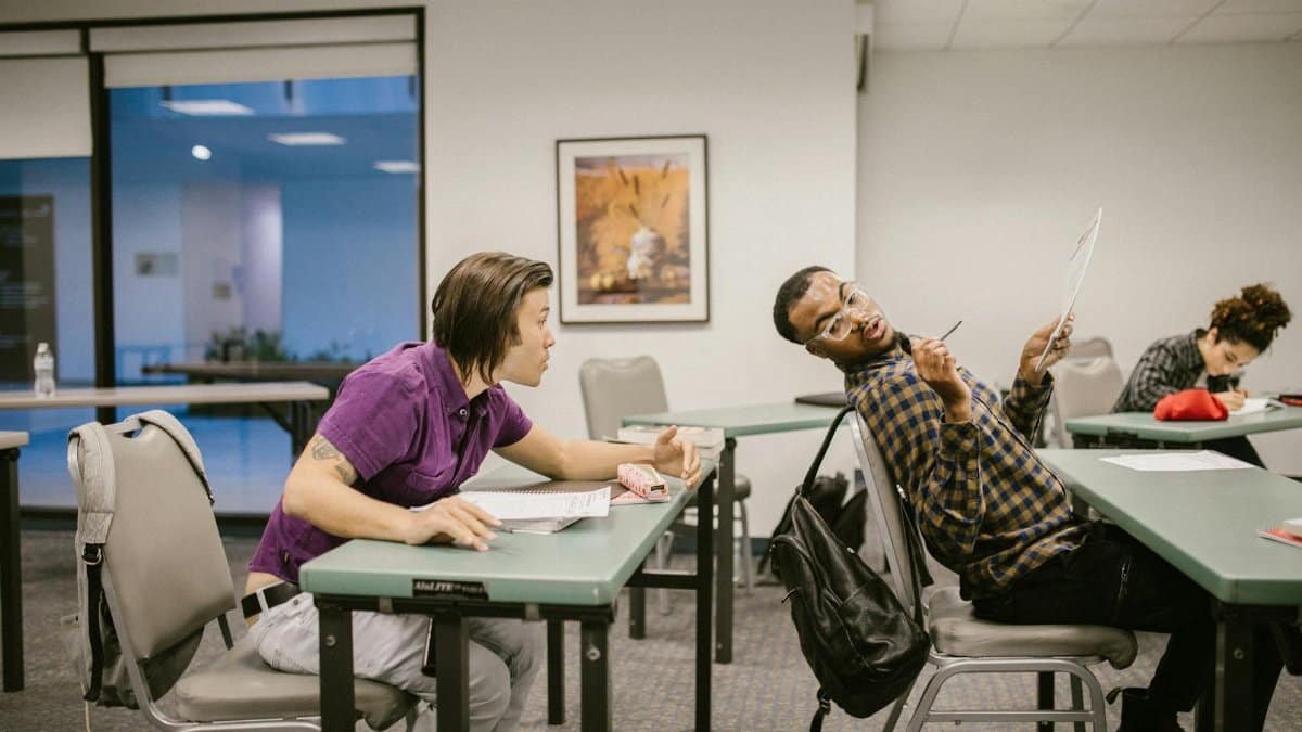 Students caught cheating during an exam in a college classroom setting, showcasing academic misconduct.