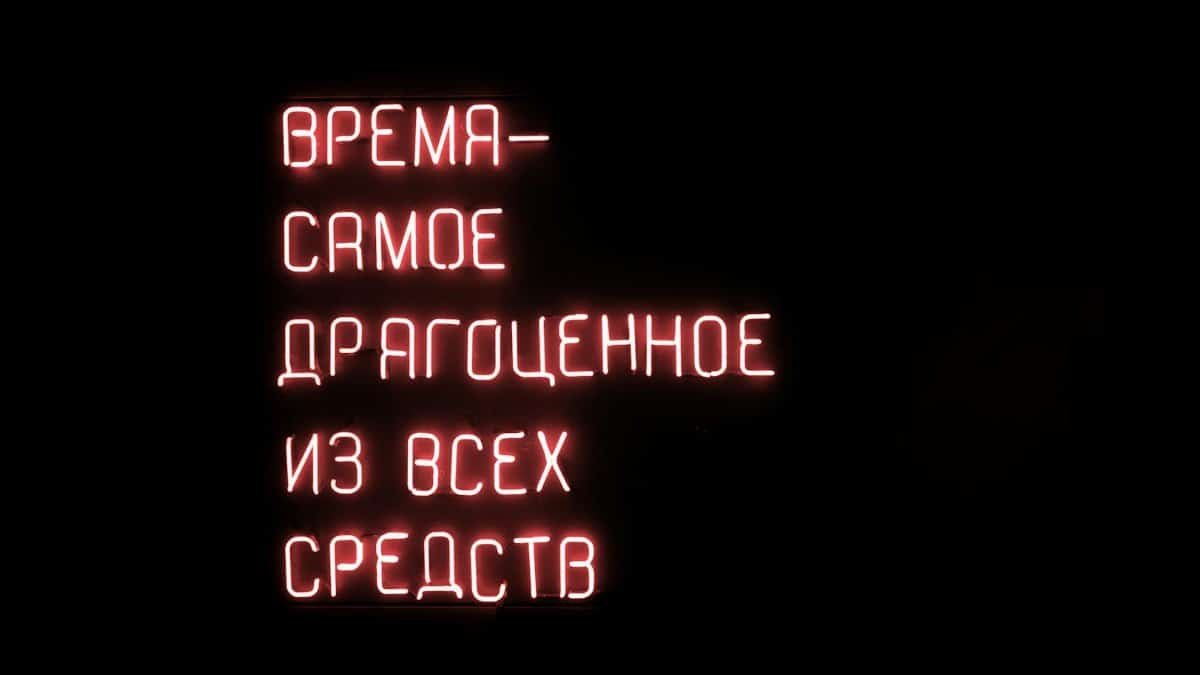 Glowing red neon sign with a motivational Russian text on a dark background.