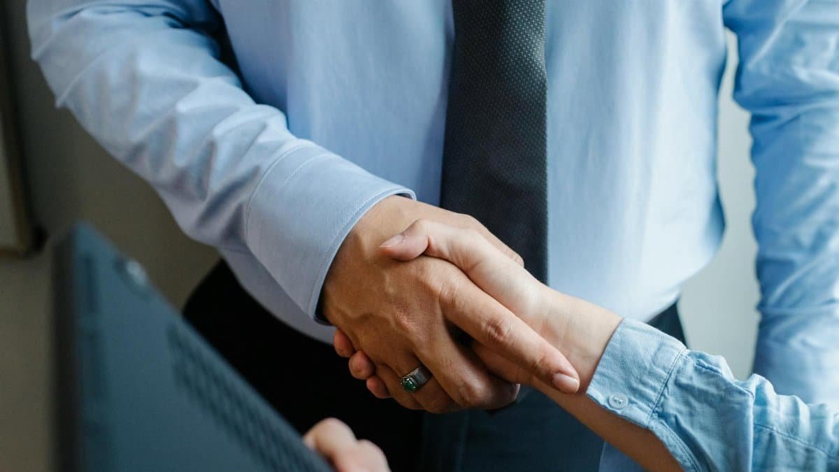 High angle of crop unrecognizable male and female business partners in formal clothes shaking hands after successful deal