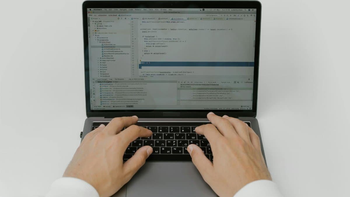 Close-up of hands coding on a laptop, showcasing software development in action.